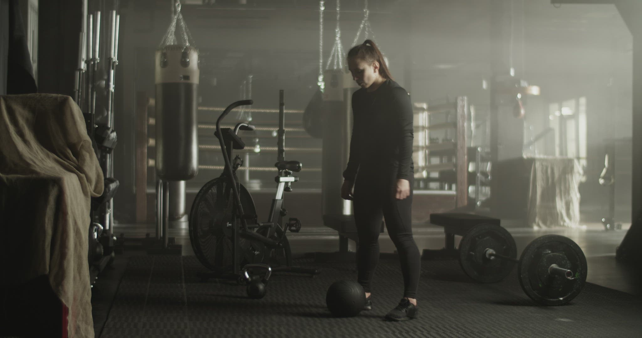 Strong young sportswoman squatting with exercising with heavy medicine ball