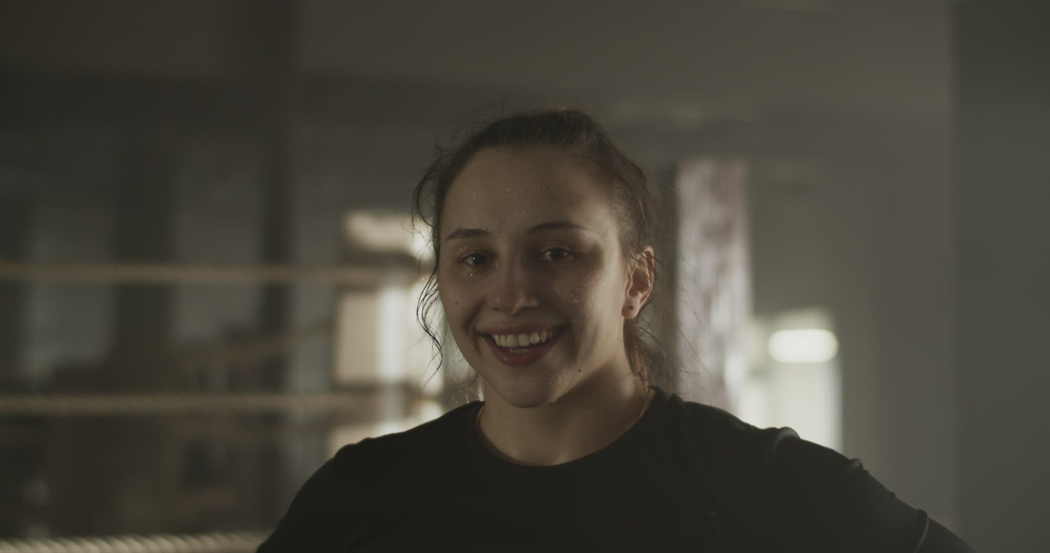 Content tired sportswoman smiling at camera after workout