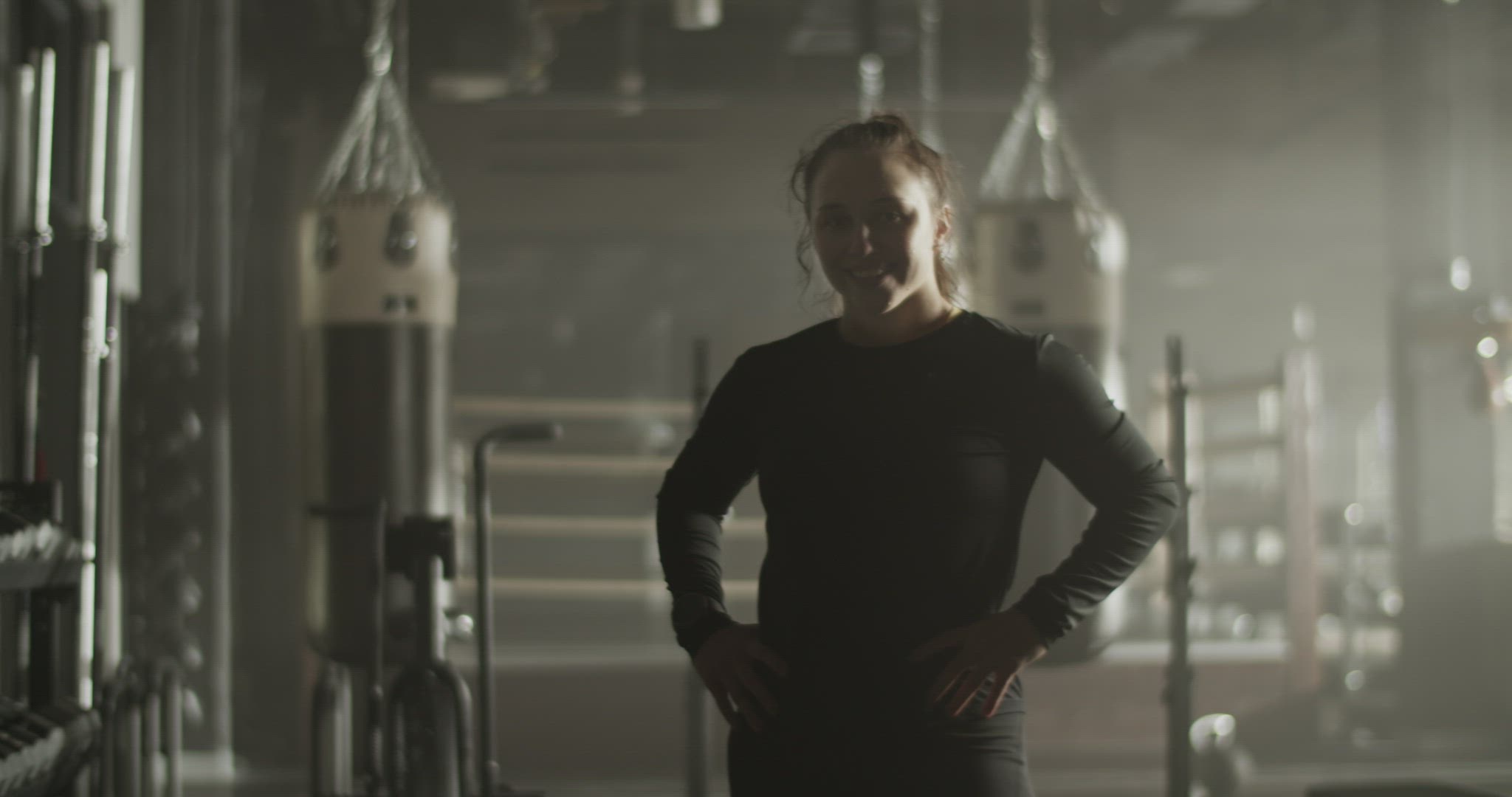 Cheerful young sportswoman smiling in gymnasium after workout