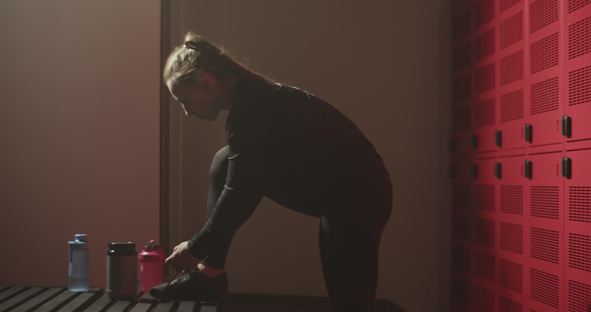 Young sportswoman tying shoelaces before training