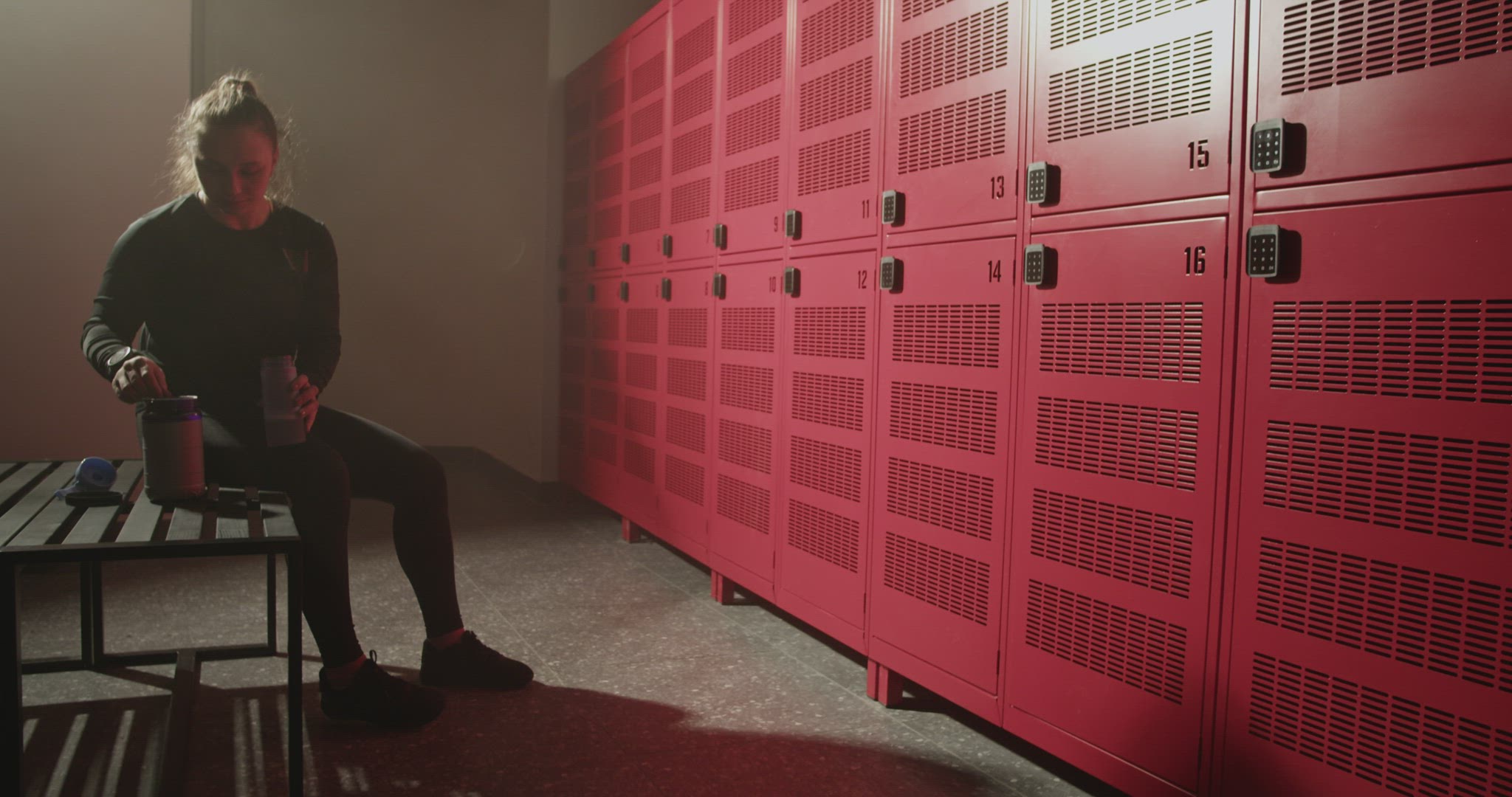Young sportswoman preparing protein cocktail in locker room before training