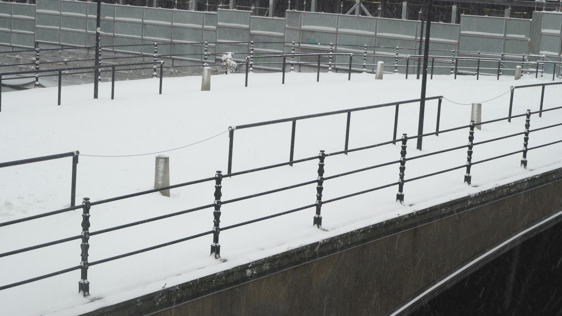 woman walking over snow covered bridge in heavy snowfall and strong wind