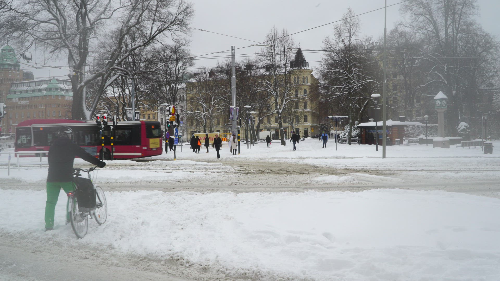 man leading bicycle on pedestrian crossing in stockholm - slushy street - snowcovered streets