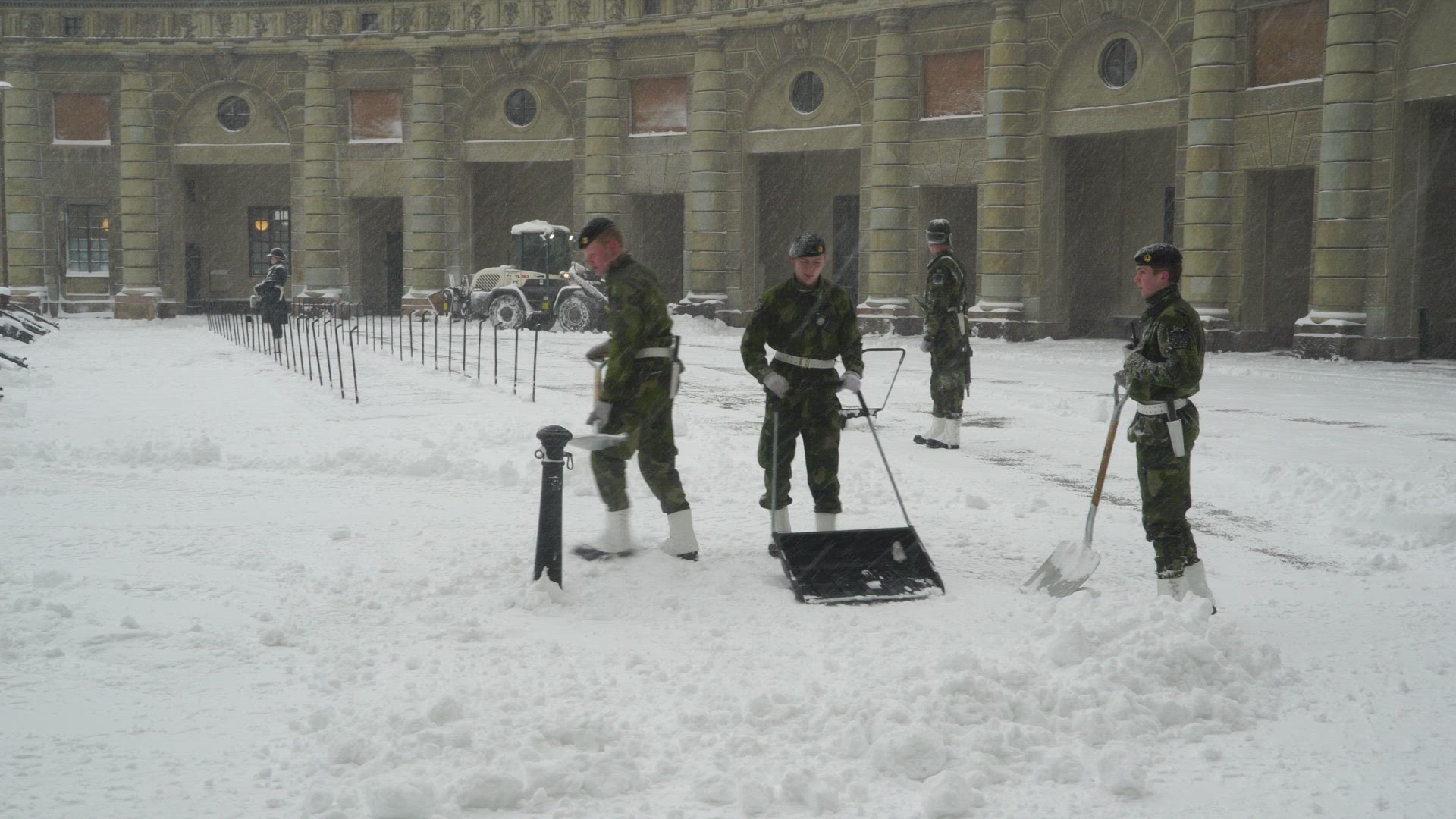guards at Stockholm Royal Palace shoveling snow - snow plow in background