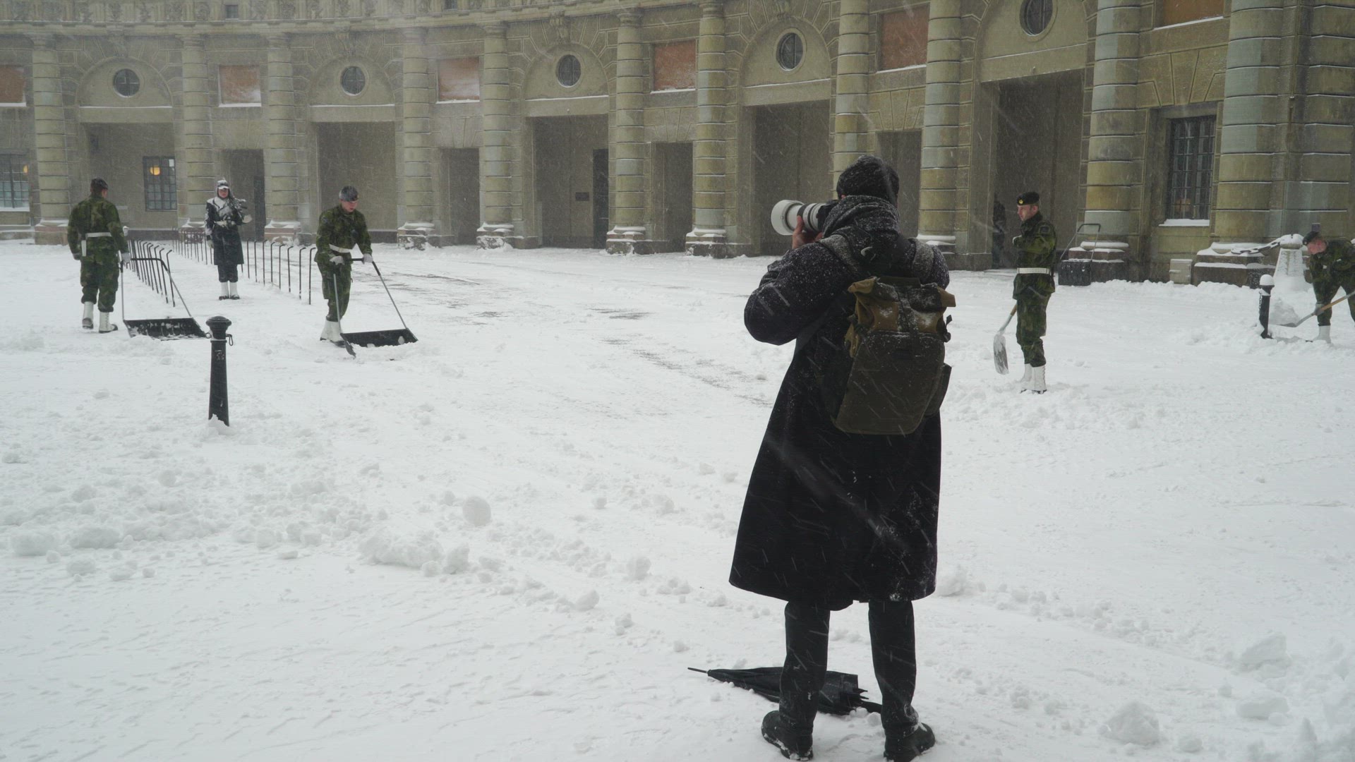 guards at Stockholm Royal Palace shoveling snow - photographer taking pictures