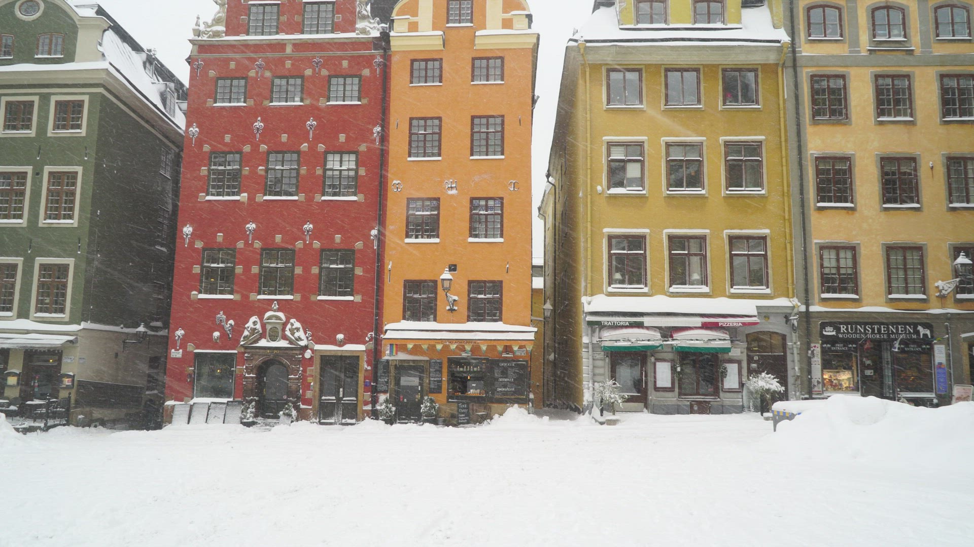 man with suitcase walking over snowcovered square Stortorget in old town in stockholm