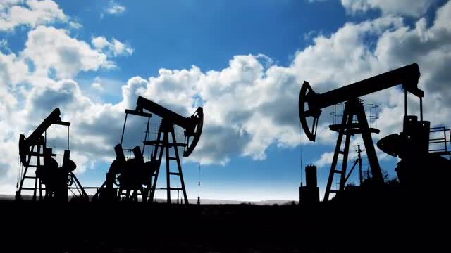 working oil pumps silhouette against timelapse clouds
