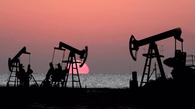 working oil pumps silhouette against sunrise