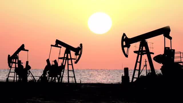 working oil pumps silhouette against sunrise