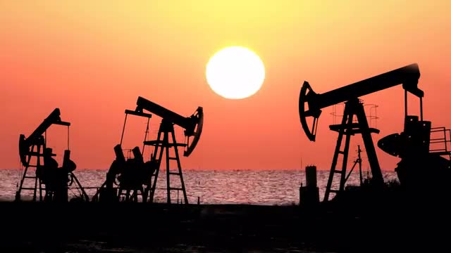 working oil pumps silhouette against timelapse sunrise