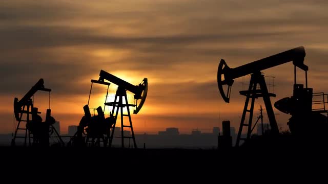 working oil pumps silhouette against sunrise