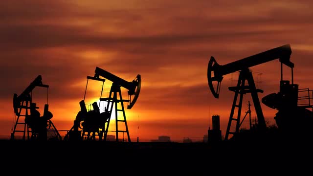 working oil pumps silhouette against timelapse sunrise