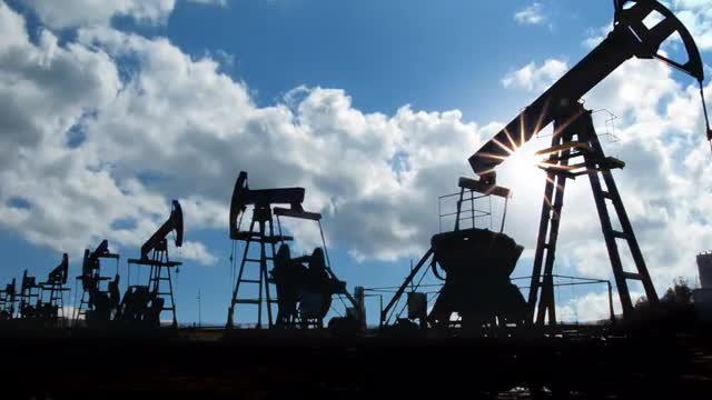 working oil pumps silhouette against timelapse clouds