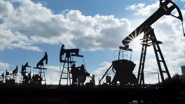 working oil pumps silhouette against timelapse clouds
