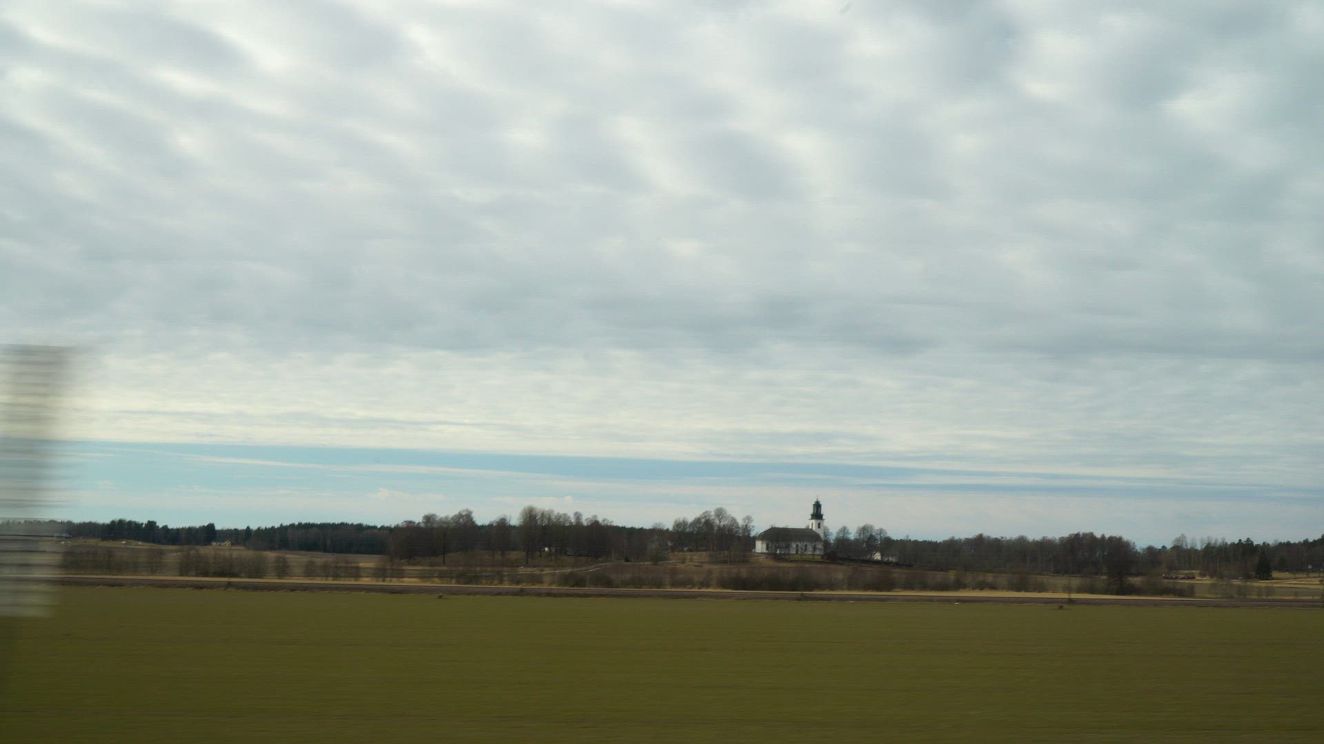 side window view from bus - landscape with fields and church - point of view