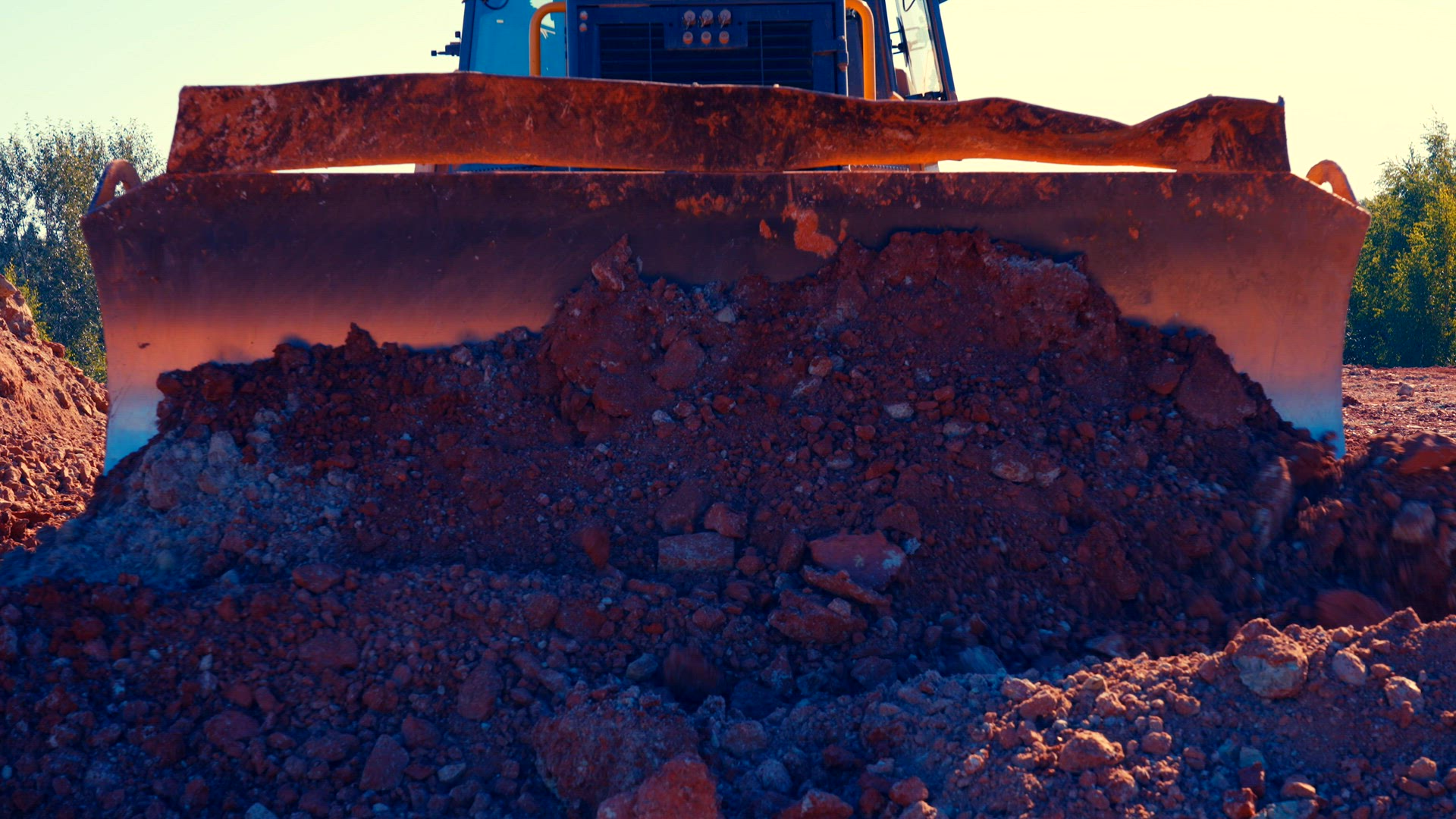 Bulldozer pushes clay towards camera.
