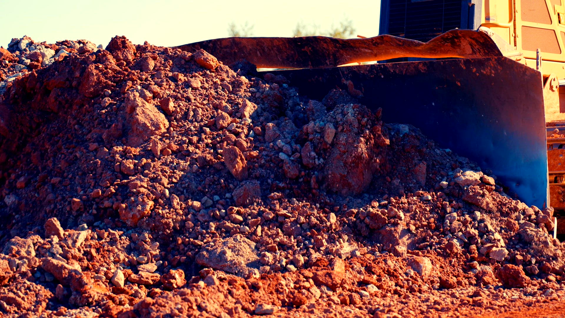 Bulldozer pushes clay pile.