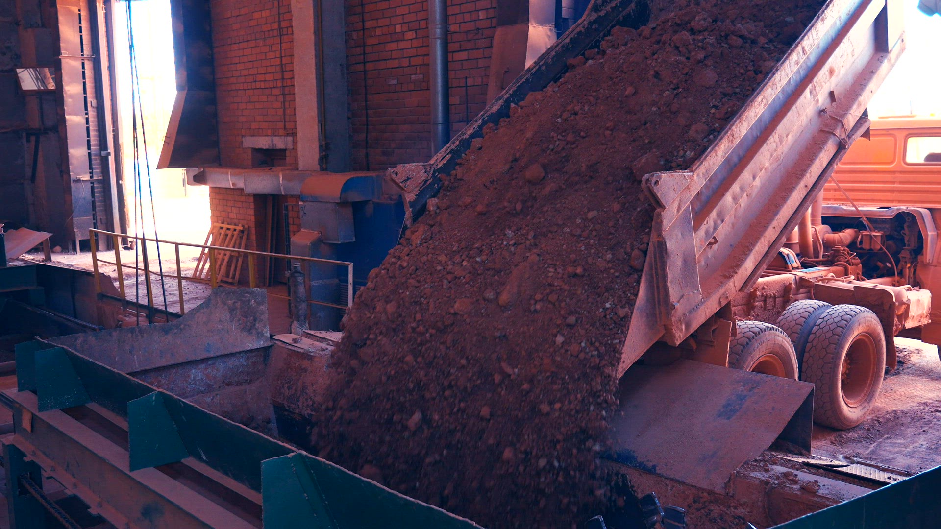 Dump Truck dumps load of clay stones.