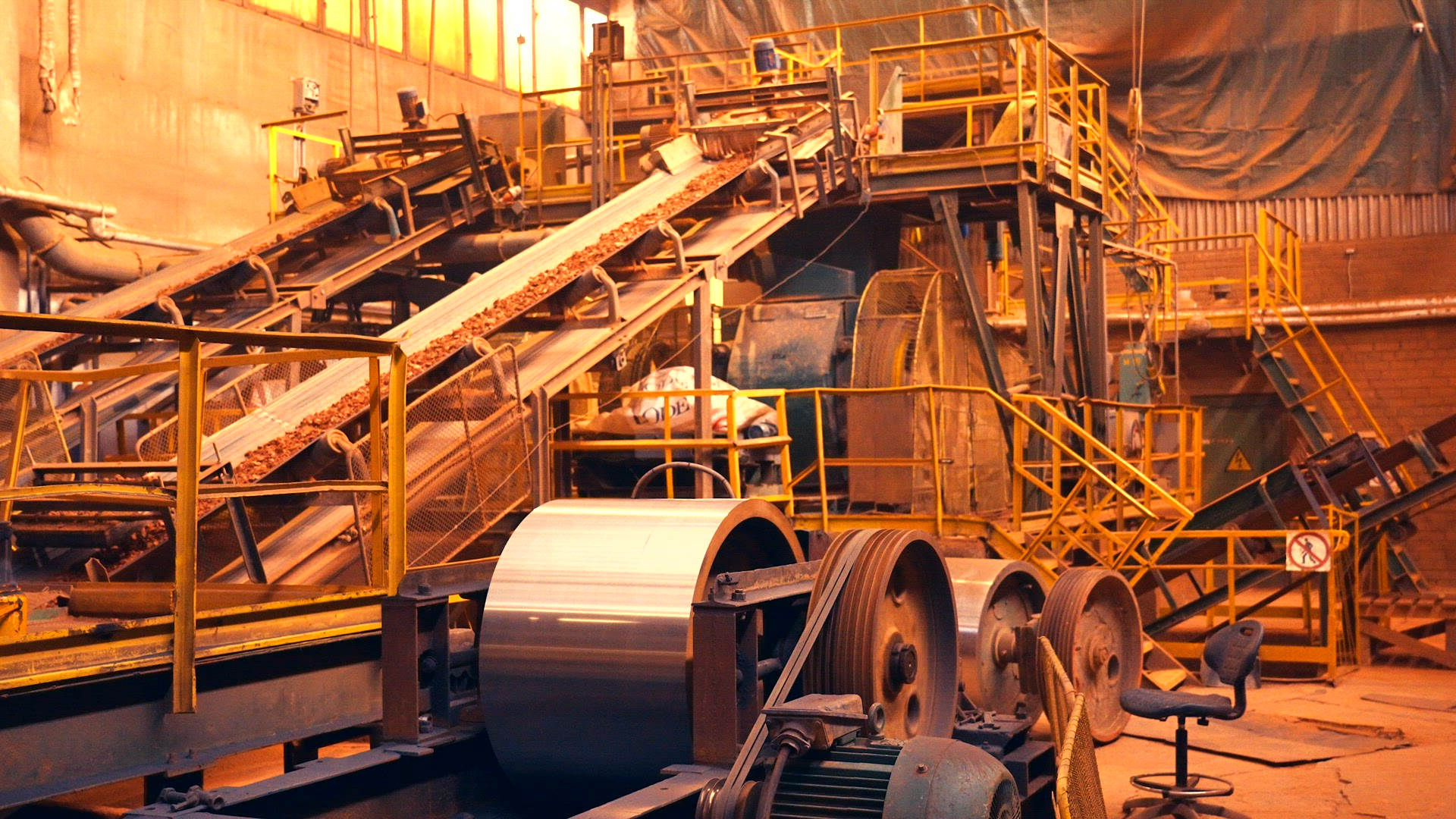 Large factory machine with several conveyor belts, large industrial belt wheels and tedders