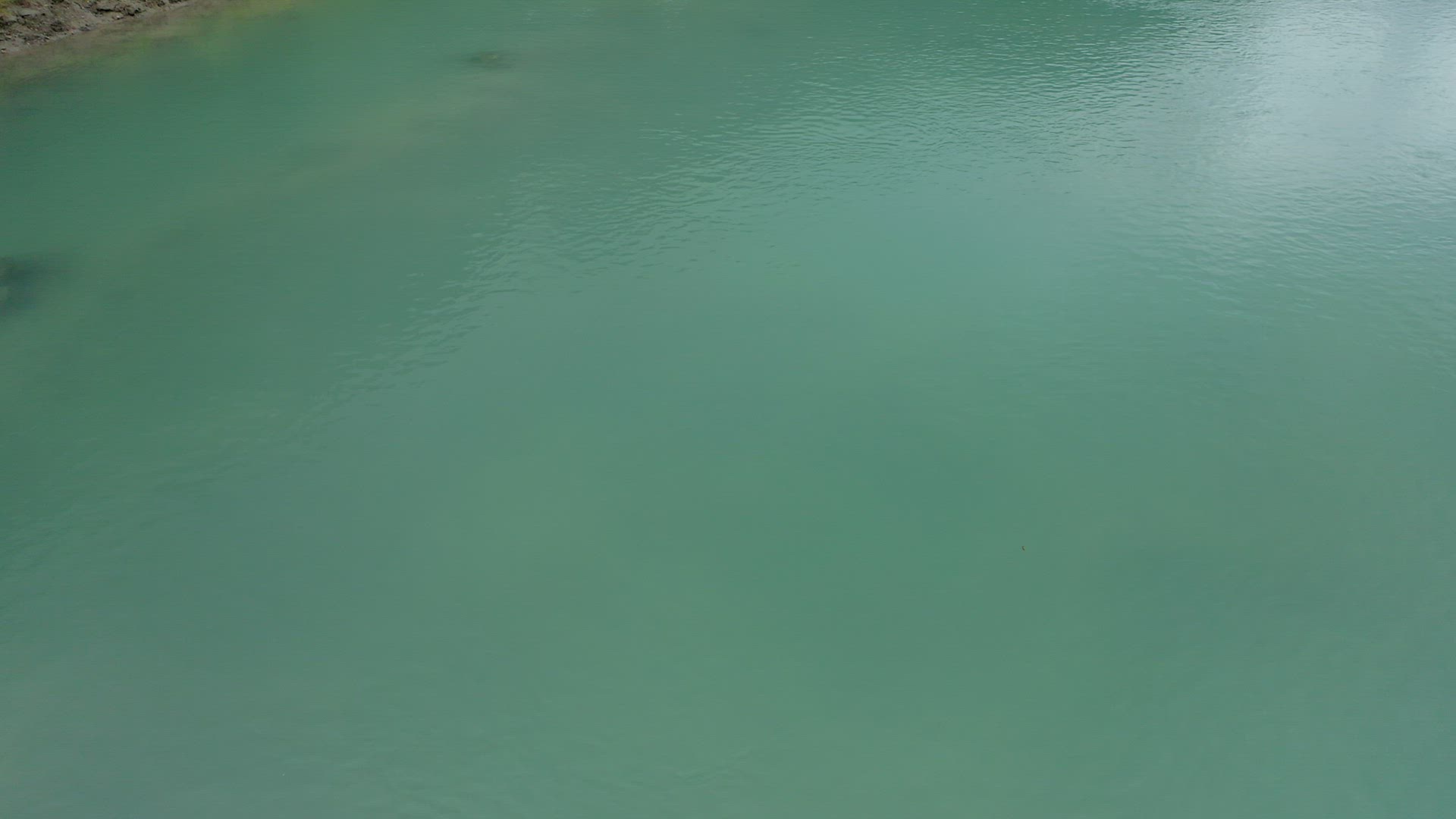 Aerial view starting with blue water river and revealing beautiful waterfall and forest in backgroun