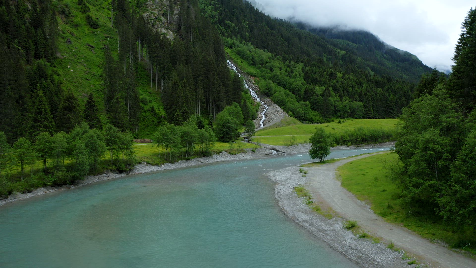 Aerial motion towards mountain river and waterfall in pine tree forest. Tirol, Austria