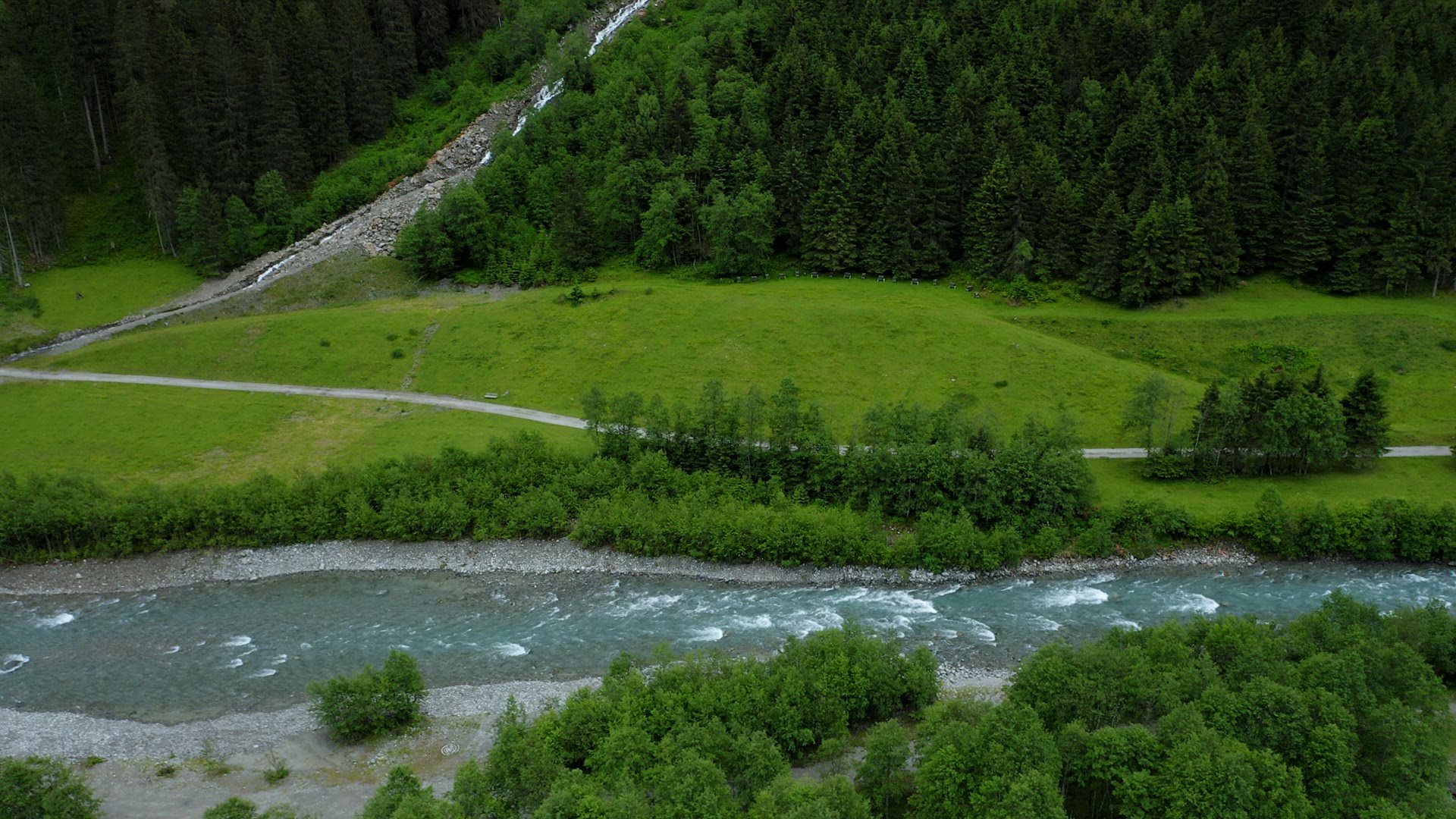 Aerial footage apline valley with river, pine tree forest and waterfall. Tirol, Austria