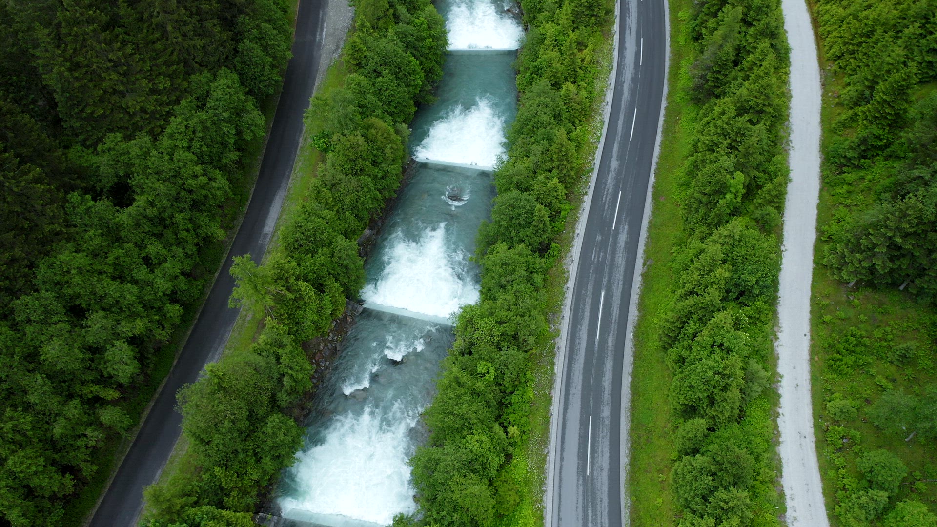 Aerial still view of mountain road behind cascade river. Tirol, Austria