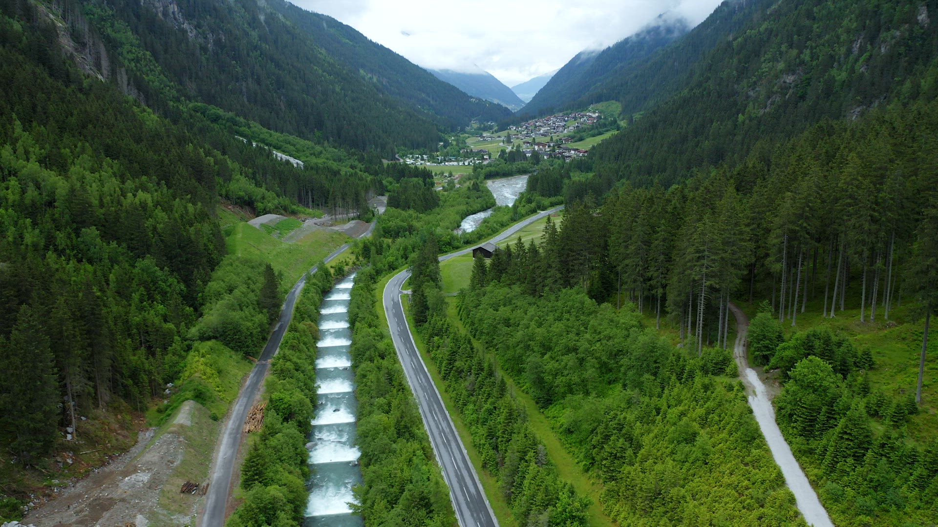Aerial view of mountain road along cascade river reveal beautiful alpine valley. Tirol, Austria