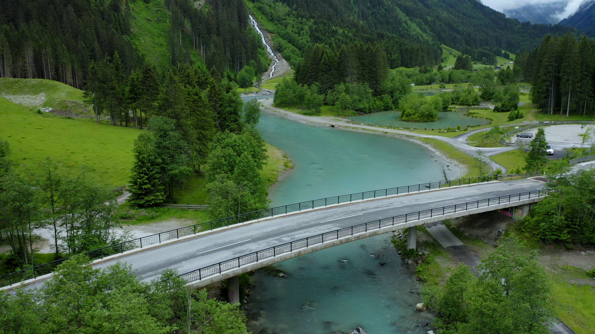 Aerial view an car driving over the bridge, blue water river and waterfall in background. Tirol, Aus