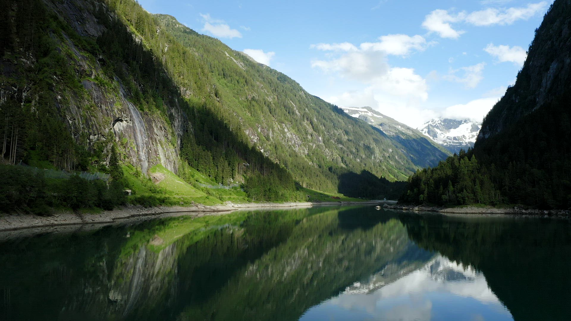 Aerial towards movement above Stillup Lake, forest and with impressive waterfall, Austria, Tyrol