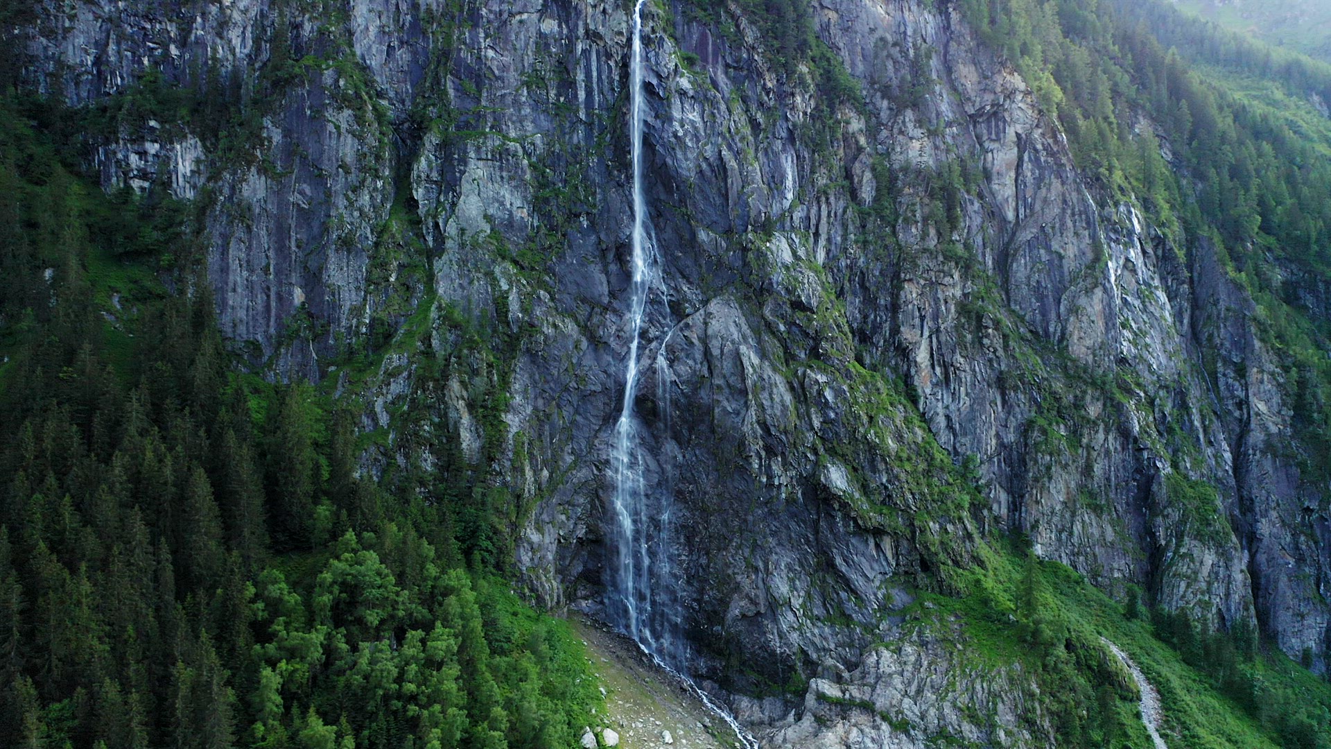 Aerial view of beautiful waterfall falling down the cliffs into Stillup Lake, Austria, Tyrol