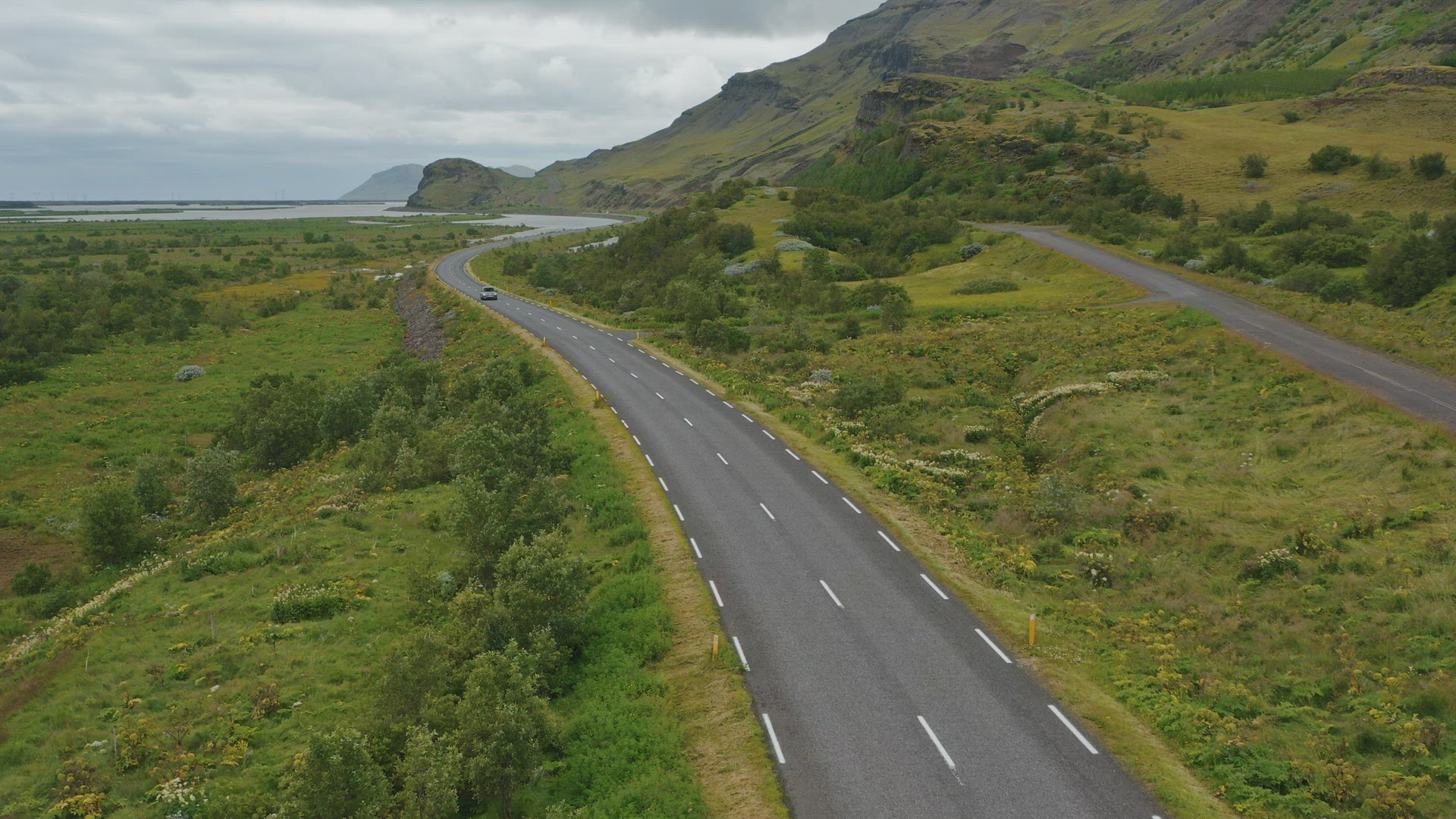 Aerial drone shot of car driving along road in Iceland