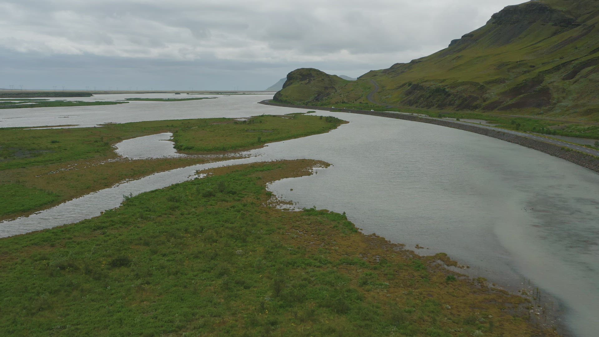 Drone shot of a scenic Icelandic landscape with road in the background running alongside a lake