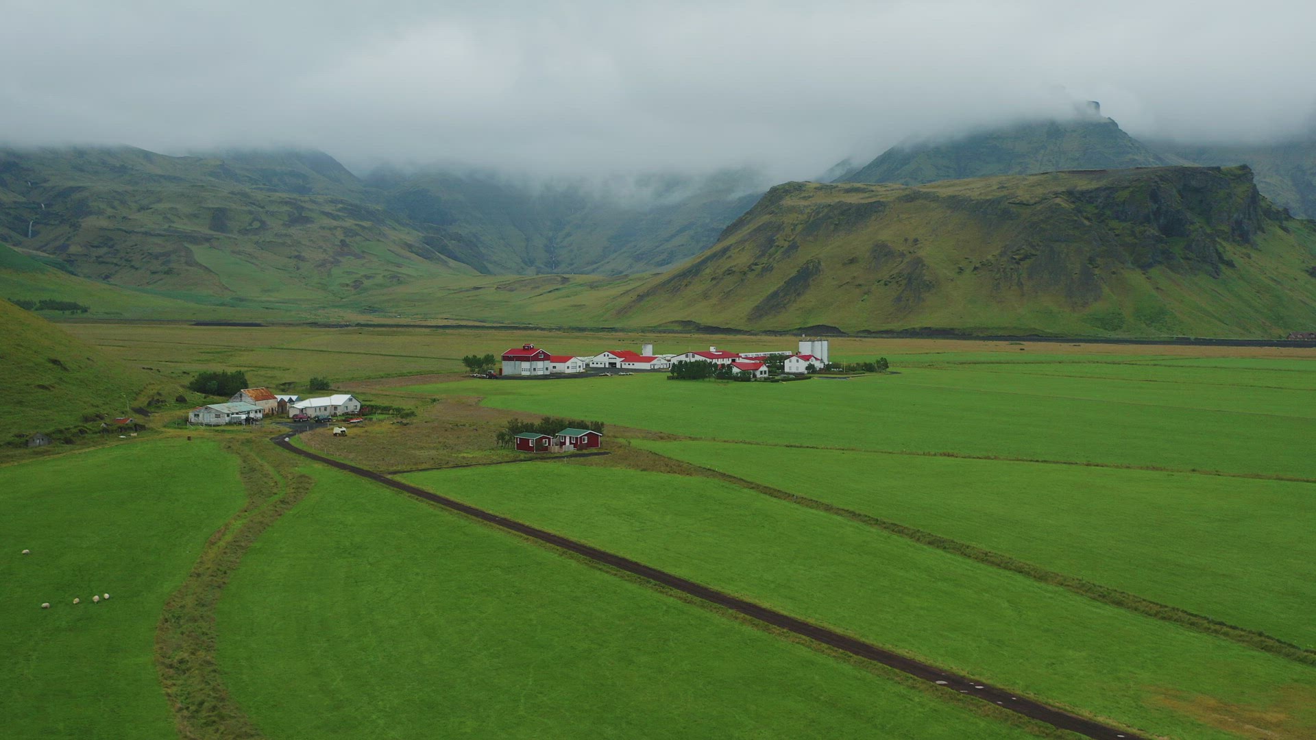 Flying over typical Icelandic farms in the green mysterious valley.