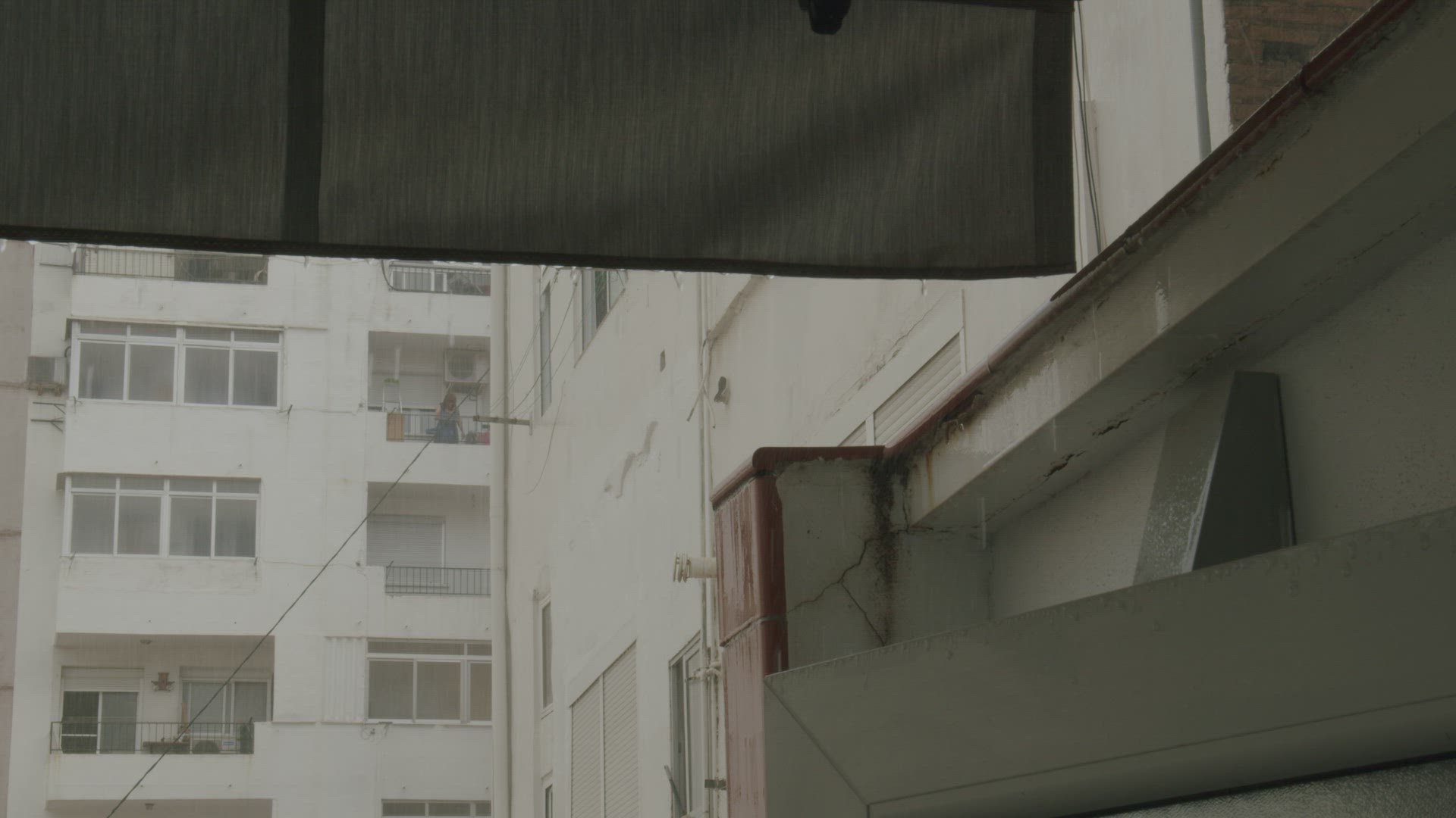 A woman stands on the balcony and looks at the rain