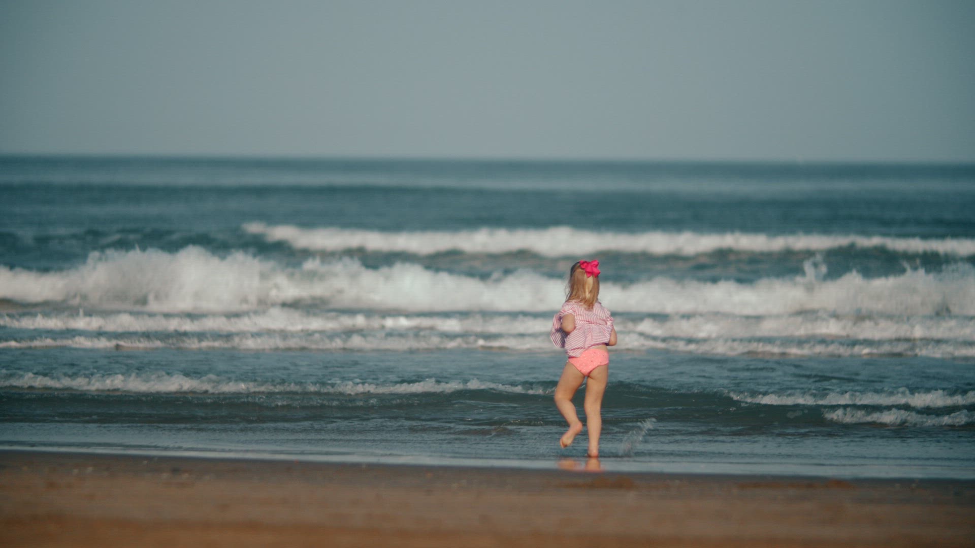 Happy barefoot child playing with ocean waves