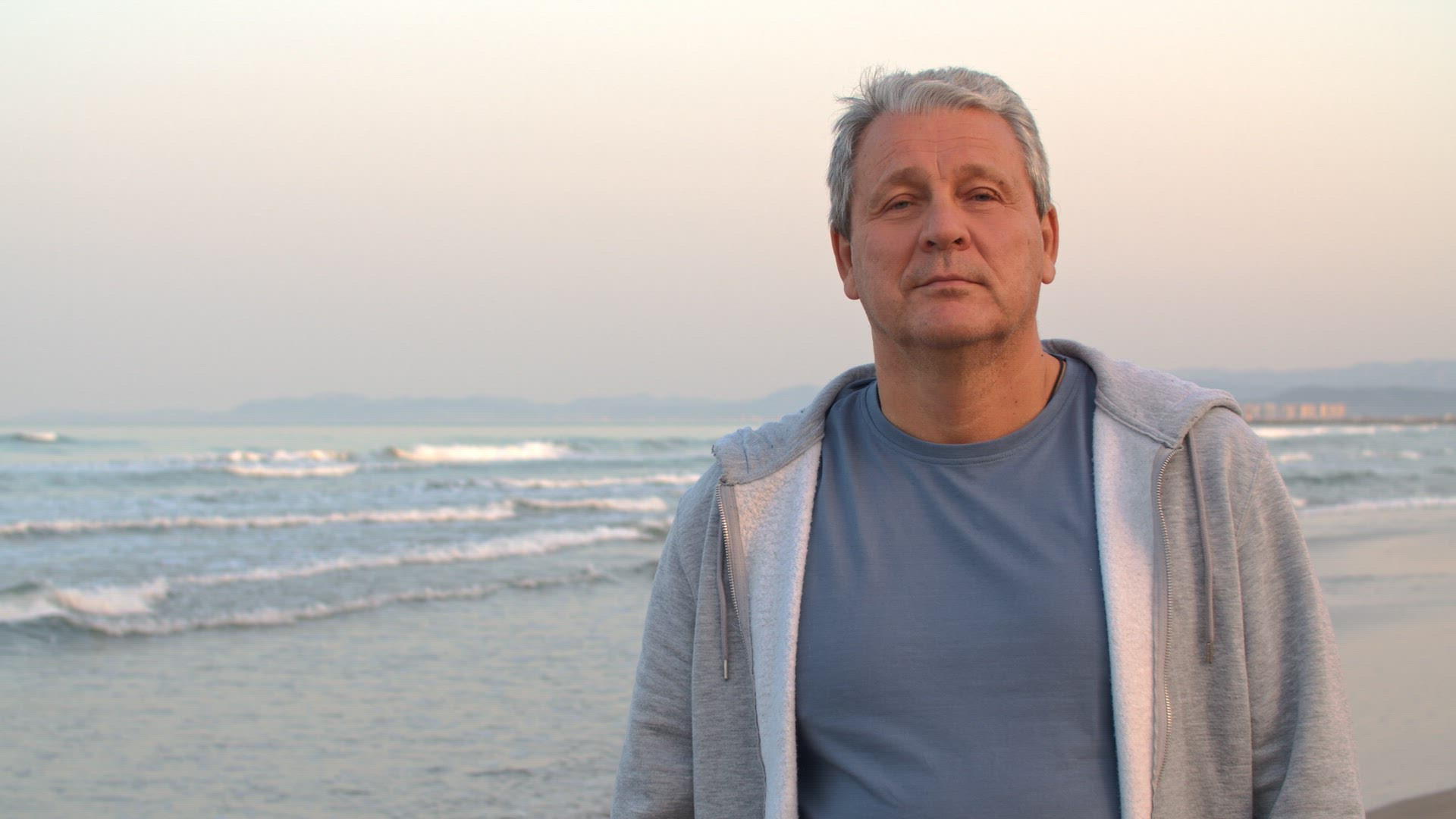 Sporty retired man with arms crossed, portrait on the beach
