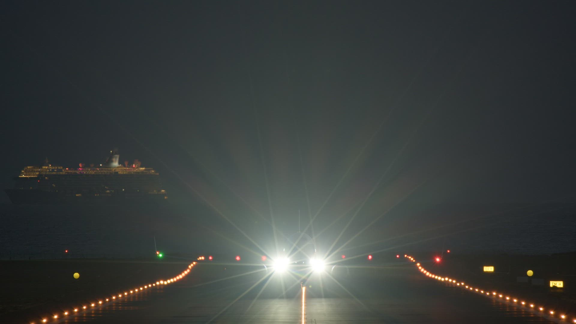 Night takeoff of an airplane against the background of a passing cruise ship