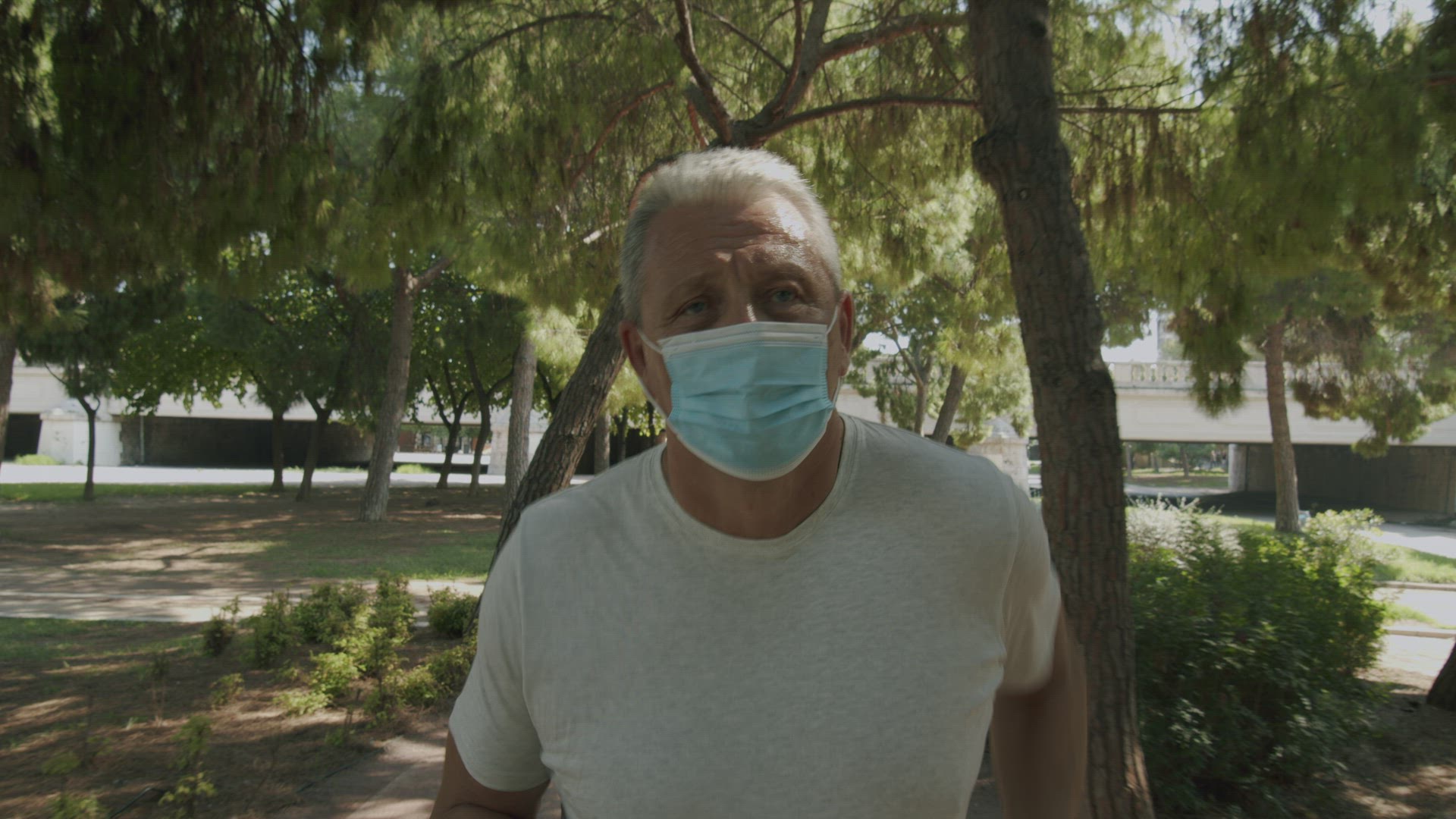 Mature man running in park with face mask