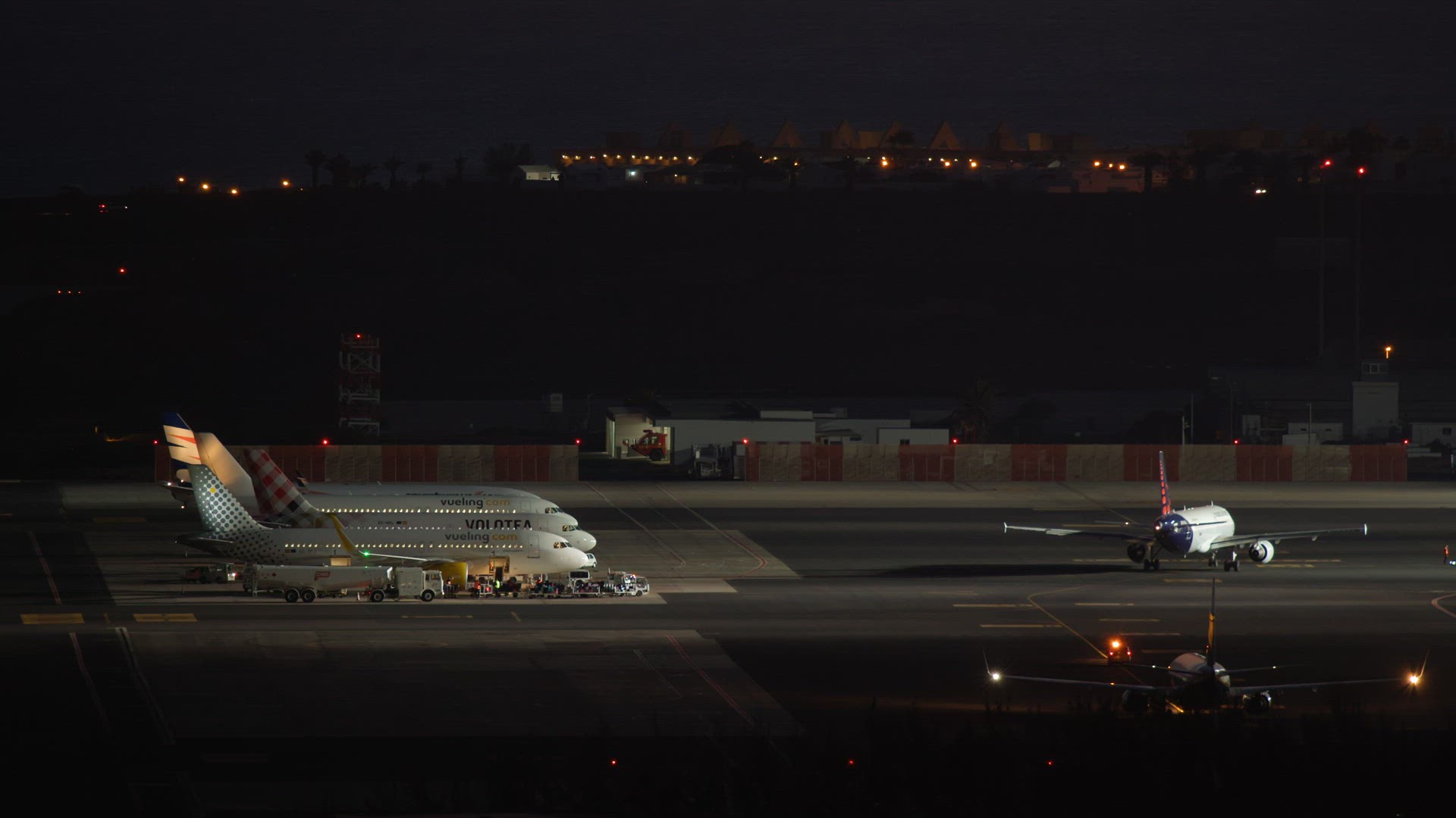 Side view of planes on the runway at the airport at night