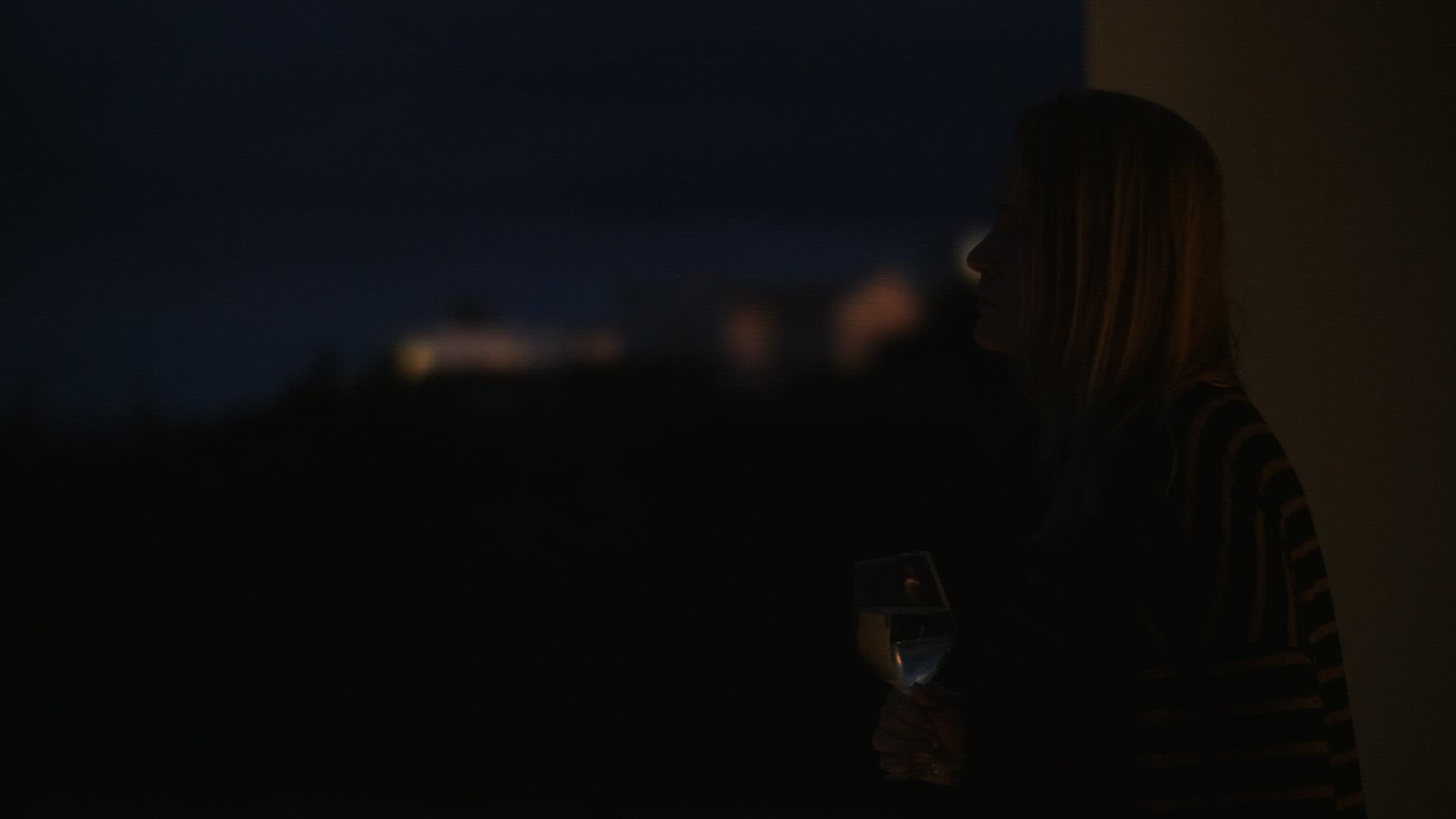 Woman enjoying wine on the balcony at night