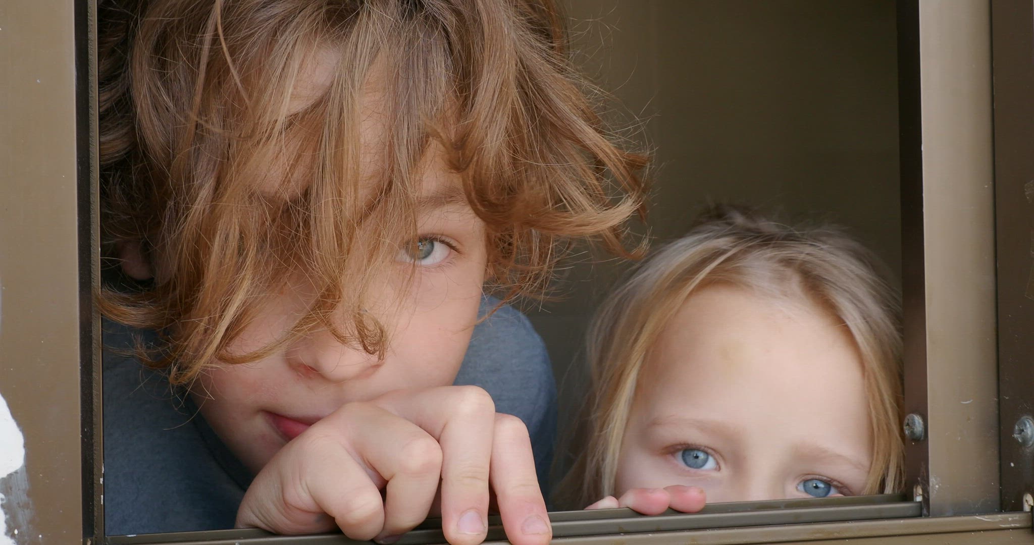 Brother with junior sister looking out of the open window