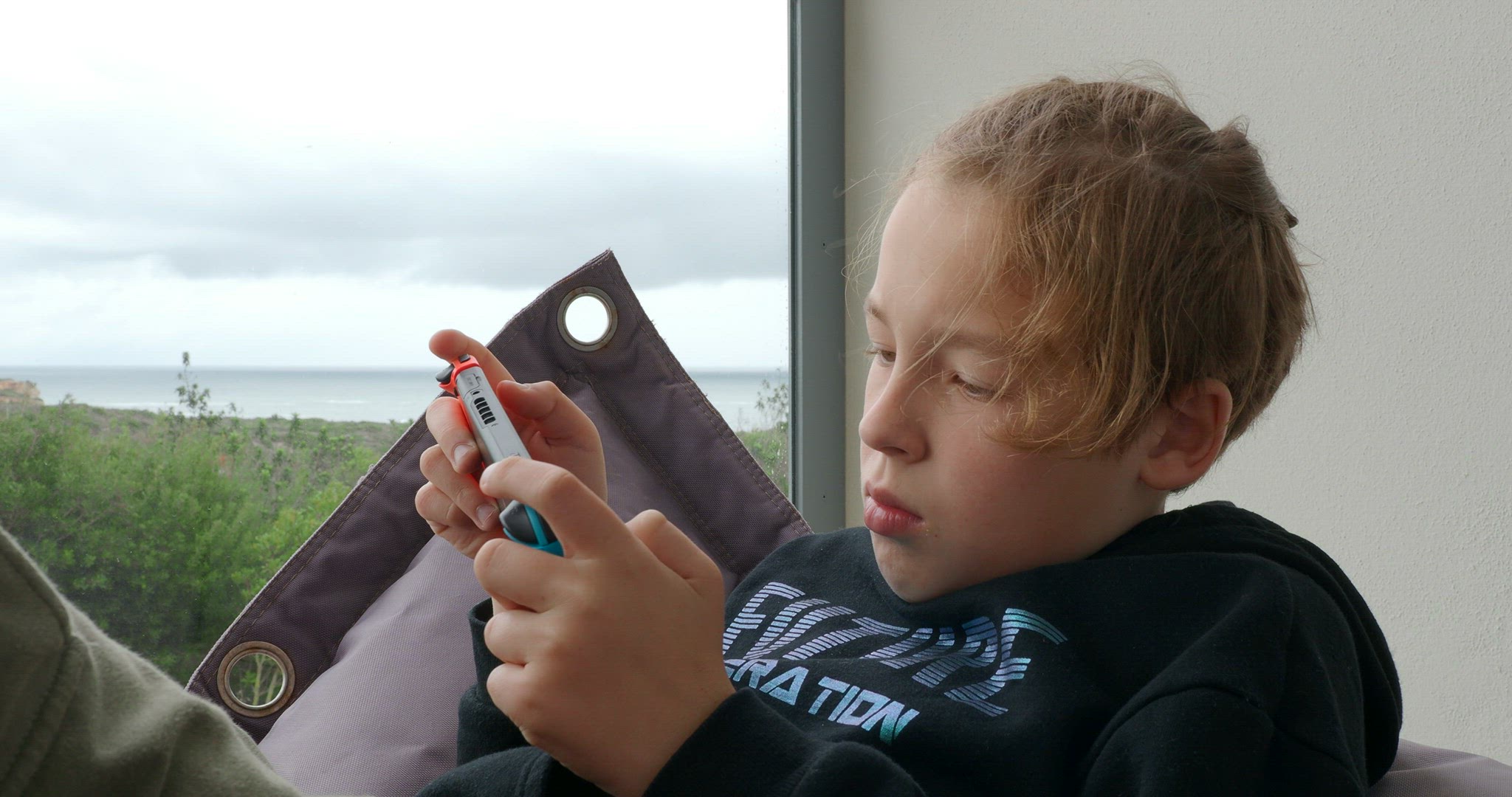 Boy teenager with portable game console at home