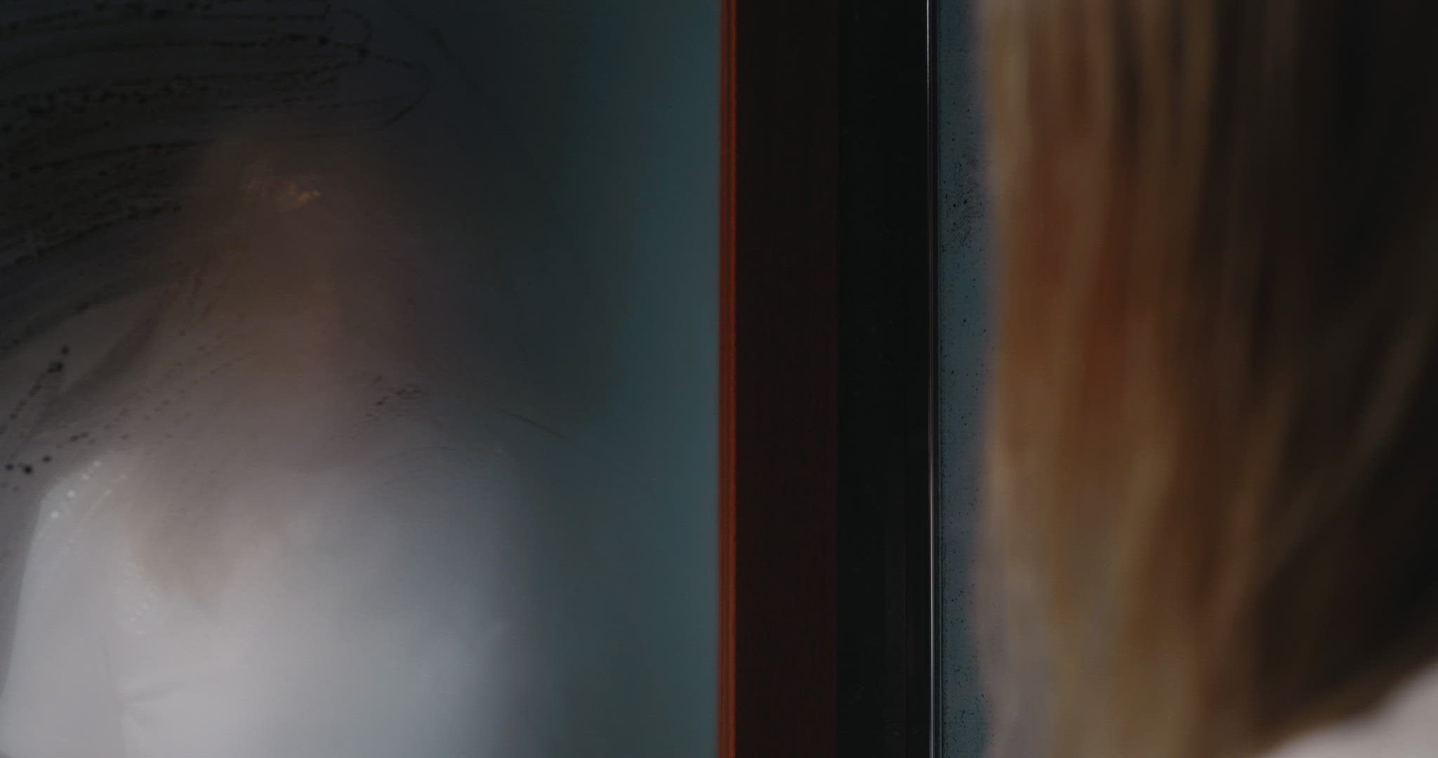 Depressed woman looking in steamy mirror