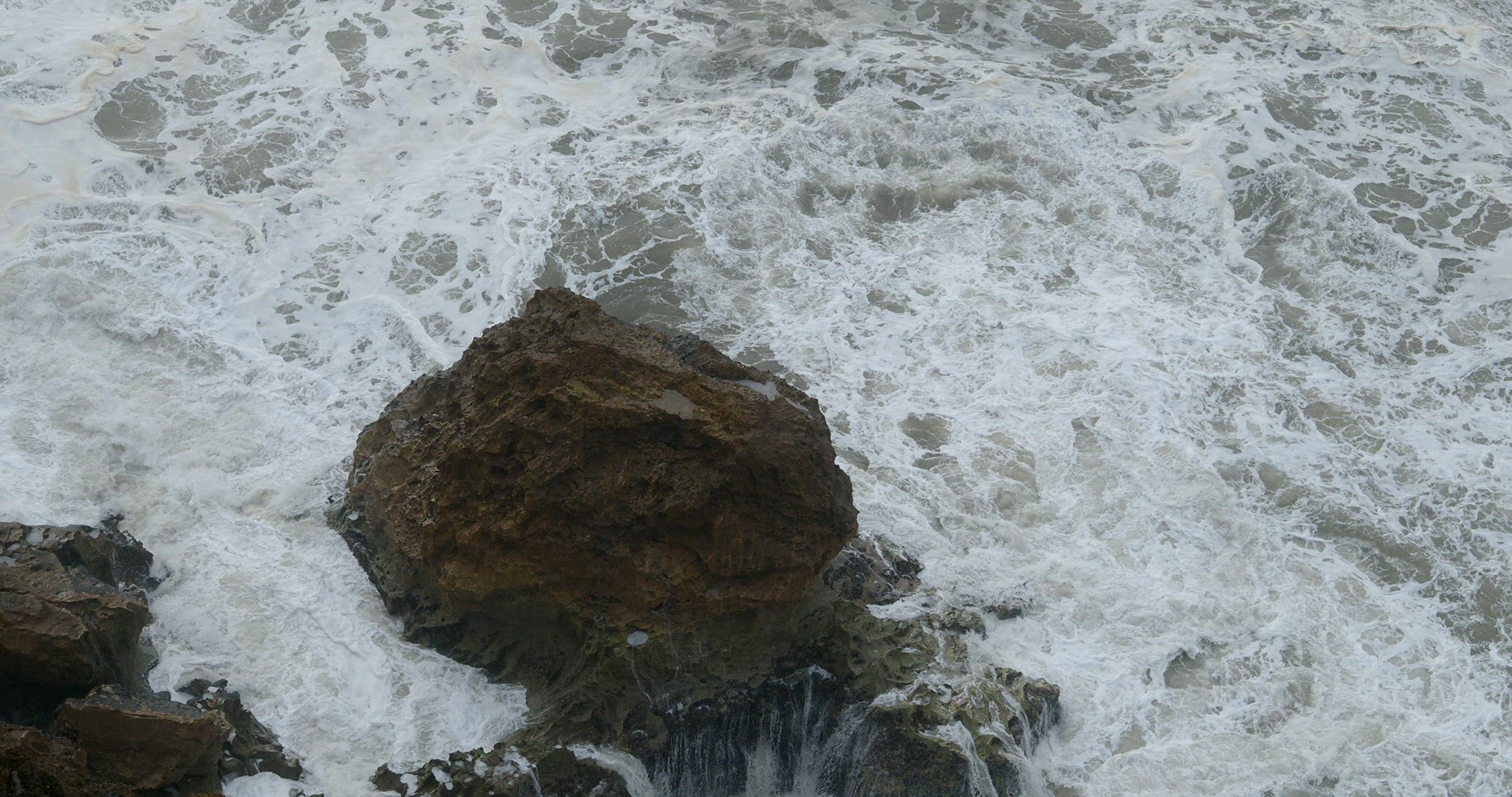 Foamy ocean water and big coastal rocks