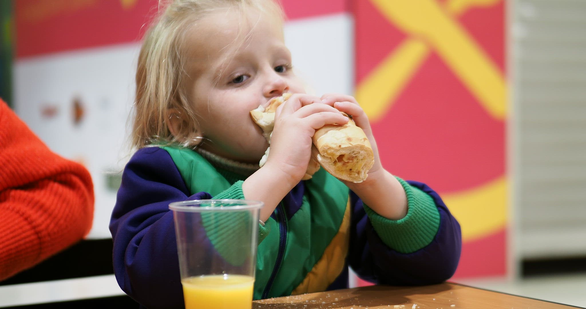 Kid eating hot dog with orange juice