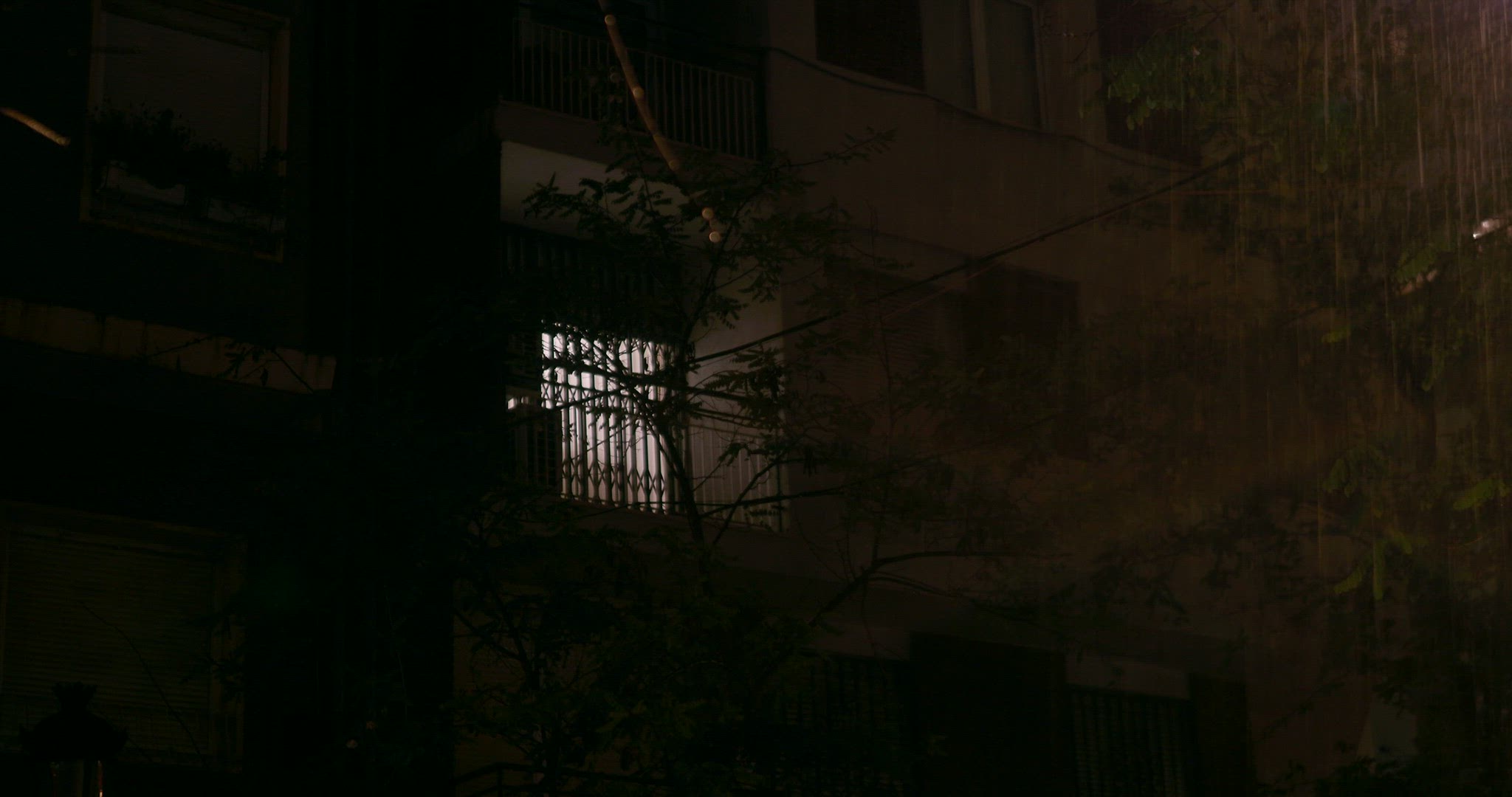 Night rain with lightning, outside view of apartment house with closed windows
