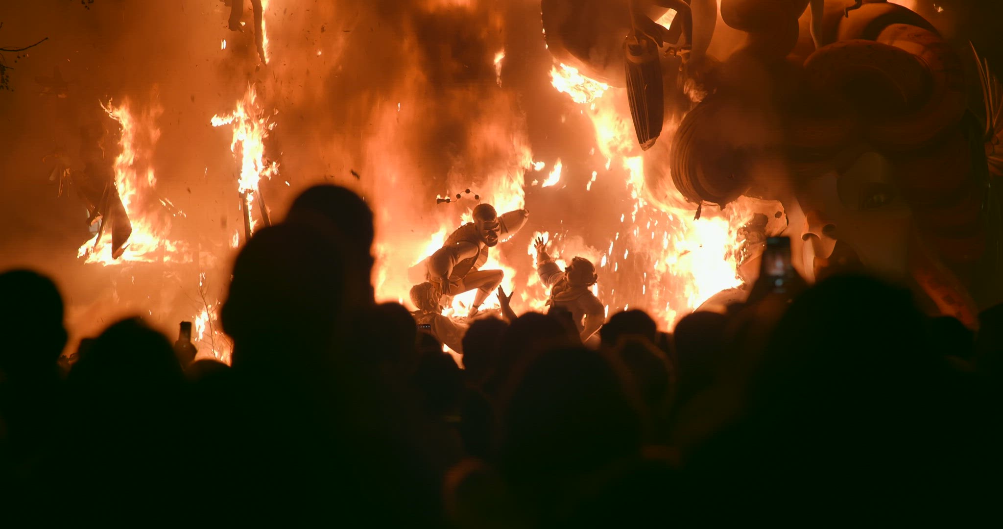 People looking at ninot in fire during Fallas celebration in Spain