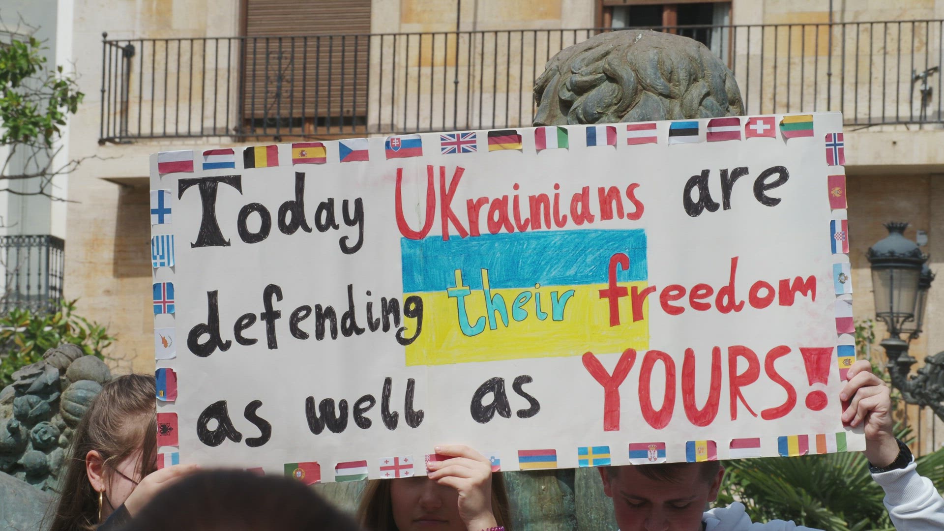 A crowd of young people at a rally in defense of Ukraine with banners