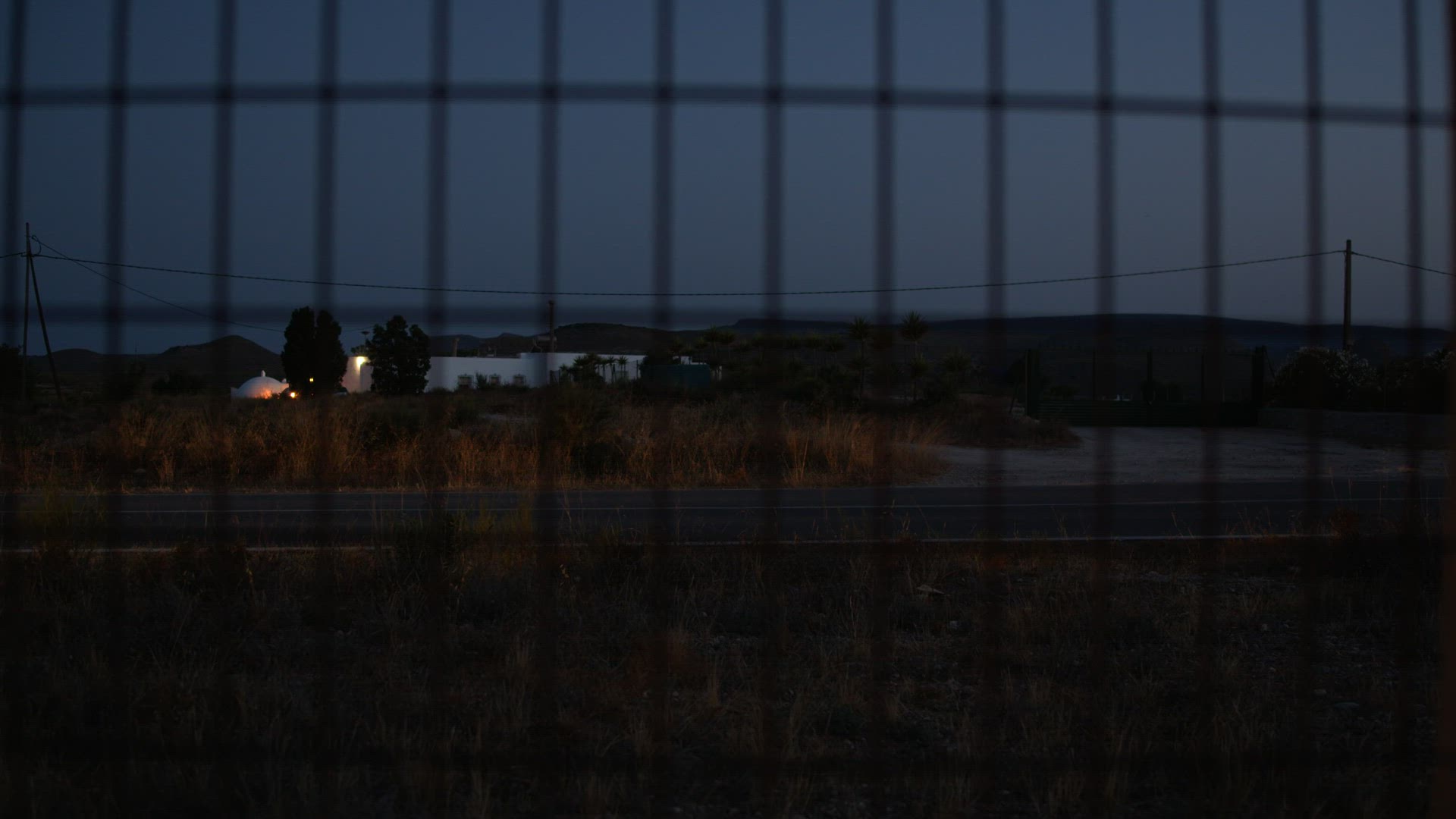 Car passing by, night view from behind the wire metal fence